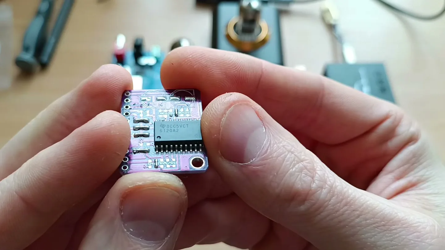 Небольшая фиолетовая плата с микросхемой TPA6120A2 от Texas Instruments в руках